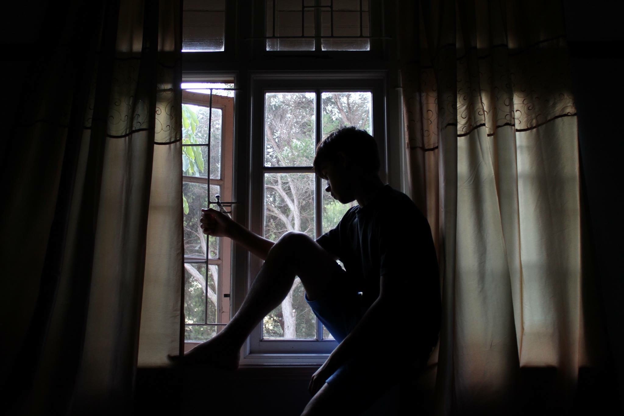 Man looking Windows Dark. Thinking in Front of Window boy siluette. Долгое размышление